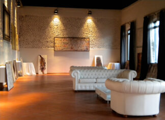 Poltrone Chesterfield in pelle bianca, da cornice ad una mostra d'arte contemporanea.
